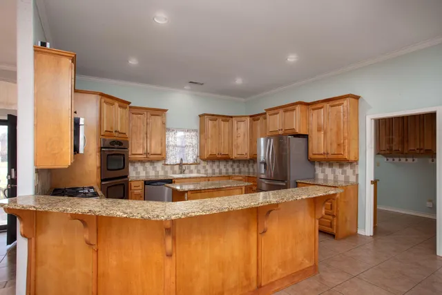 a kitchen with stainless steel appliances granite countertop a sink stove microwave and refrigerator