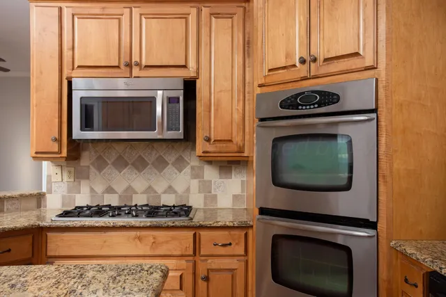 a kitchen with granite countertop a stove top oven microwave and cabinets