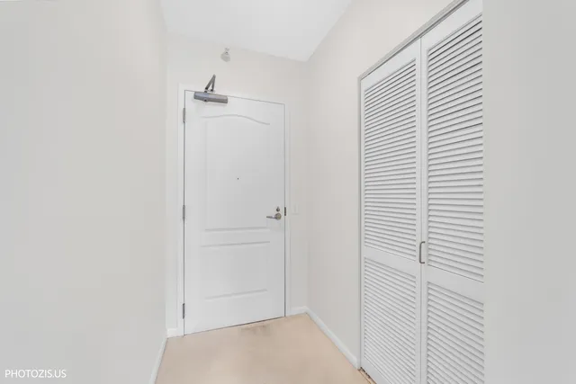 a view of a hallway with stainless steel appliances granite countertop a refrigerator and a sink