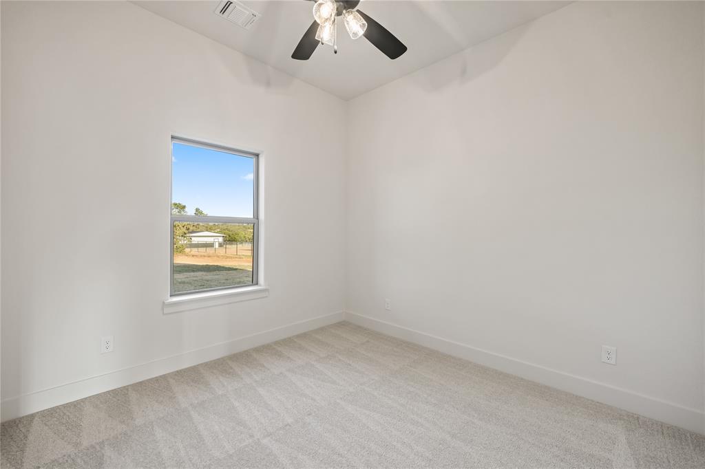 7004 Rnch Vw Place Springtown, TX 76082 - Photo 17 of 25 Neutral tone walls with an accent window, light-colored carpet, and a ceiling fan with integrated lighting