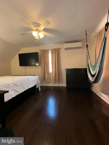 a bedroom with a bed a mirror and a flat tv screen on dresser