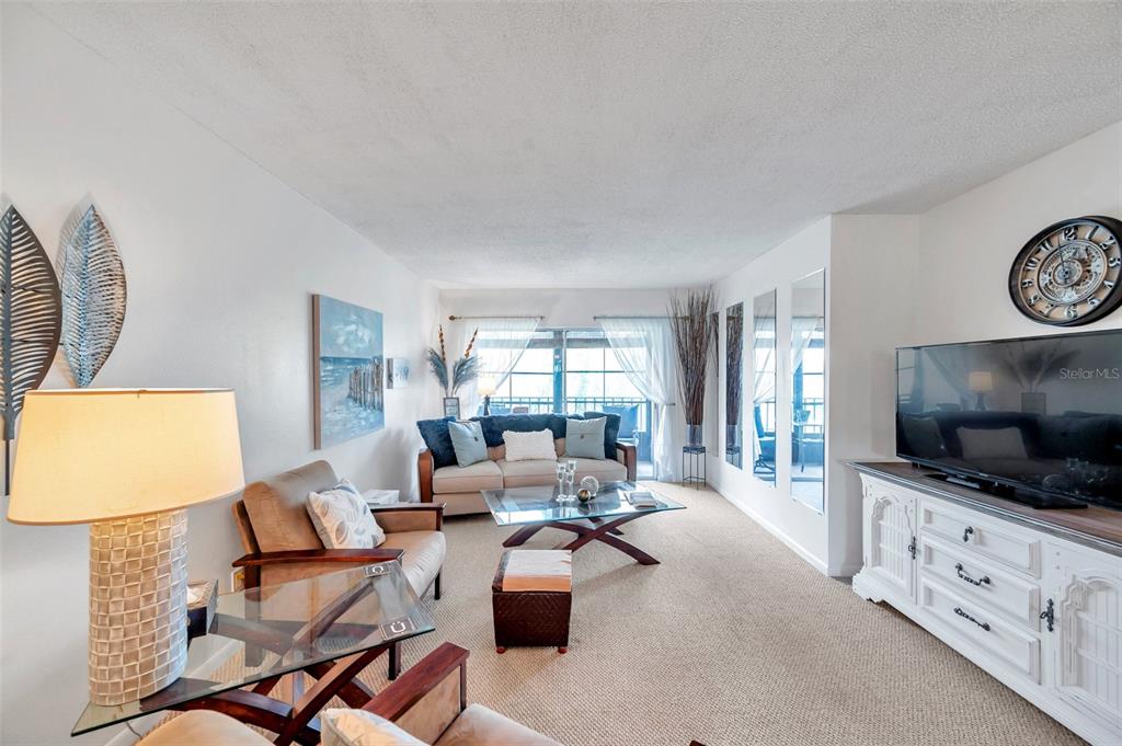 1430 Heather Ridge Boulevard, Unit 304 Dunedin, FL 34698 - Photo 11 of 36 a living room with furniture a flat screen tv and a window