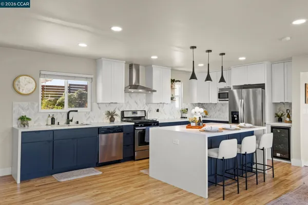 a kitchen with stainless steel appliances kitchen island granite countertop a sink a stove a refrigerator and a dining table with wooden floor