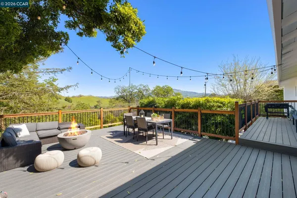 a view of a roof deck with table and chairs couches under an umbrella with wooden floor