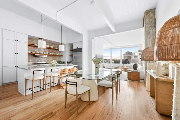 a kitchen with stainless steel appliances a dining table chairs stove and wooden floor