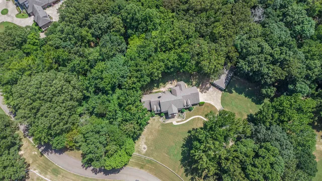 an aerial view of a house with outdoor space and trees all around