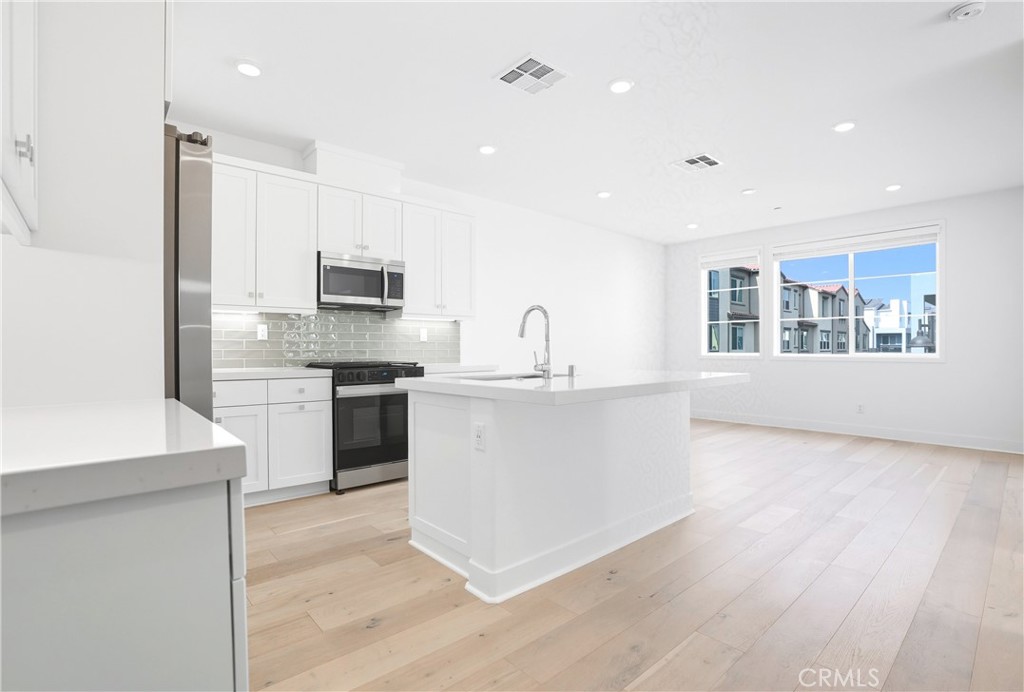 3140 Cove Street Rancho Mission Viejo, CA 92694 - Photo 2 of 69 a kitchen with stainless steel appliances granite countertop a stove top oven a sink a refrigerator and white cabinets with wooden floor