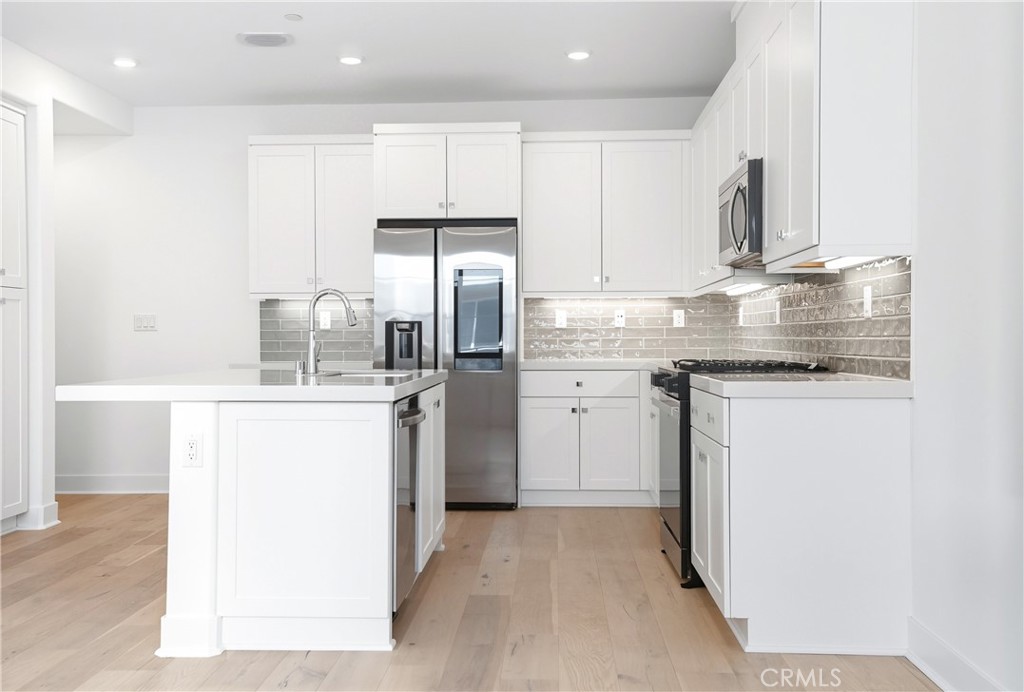 3140 Cove Street Rancho Mission Viejo, CA 92694 - Photo 4 of 69 a kitchen with a sink a refrigerator and white cabinets