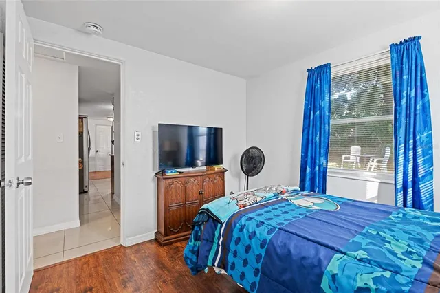 a bedroom with a large bed and a flat tv screen on dresser