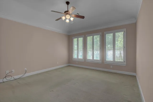 an empty room with a chandelier fan and windows
