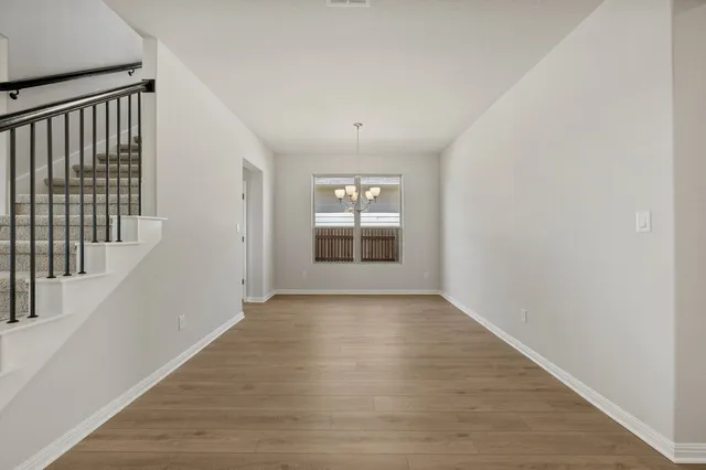 a view of an empty room with wooden floor and windows