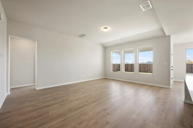 a large kitchen with stainless steel appliances granite countertop a stove a sink a refrigerator and white cabinets with wooden floor