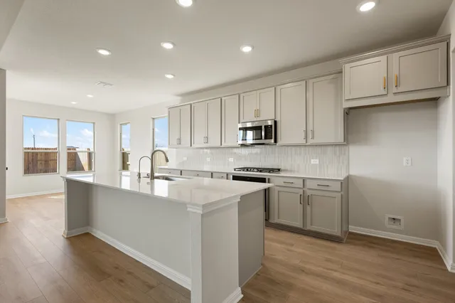 a large white kitchen with kitchen island a sink a stove a refrigerator and white cabinets
