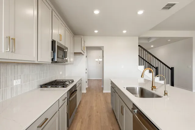 a large kitchen with stainless steel appliances granite countertop a lot of counter space and wooden floors