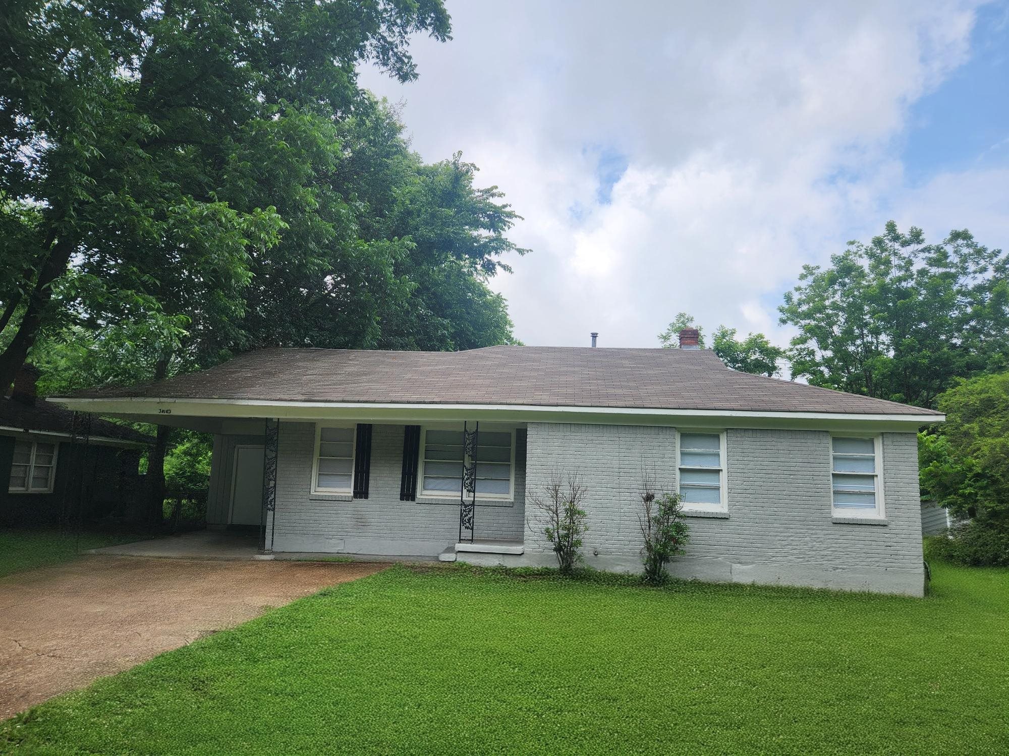 Ranch-style house with brick siding, driveway, a front yard, and a carport