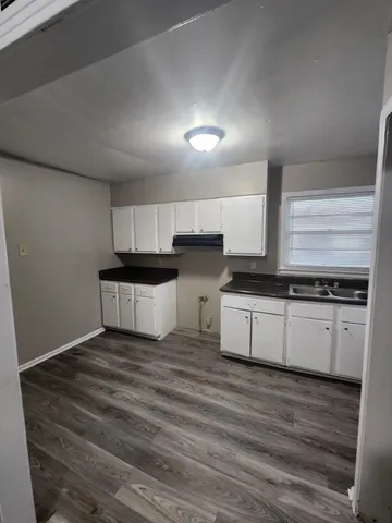 a large white kitchen with granite countertop a stove top oven a sink and white cabinets