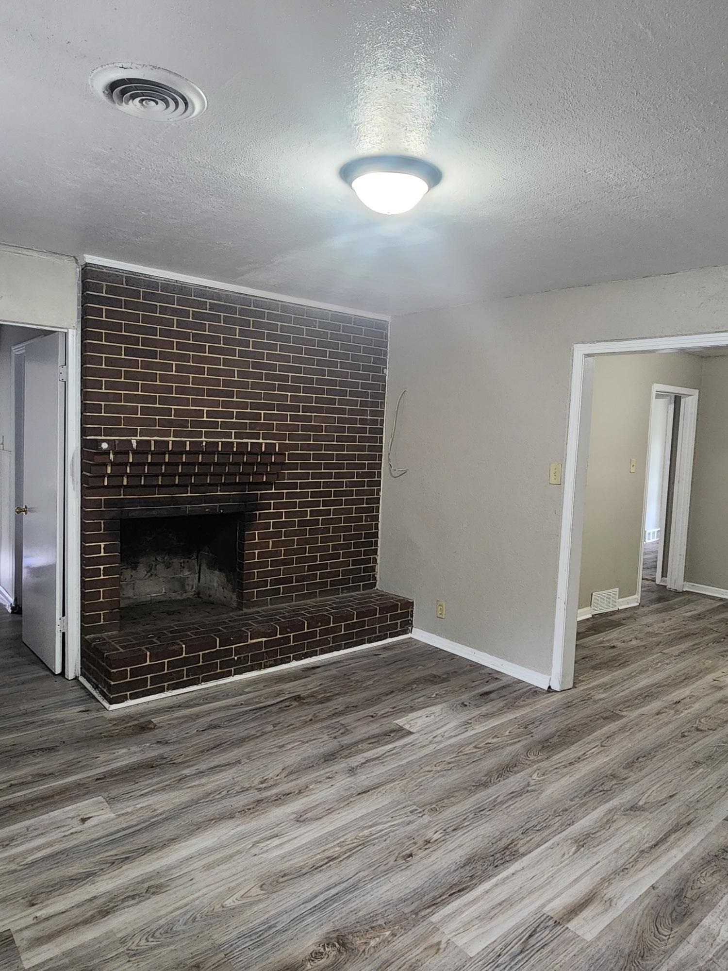 3645 Brompton Road Memphis, TN 38118 - Photo 2 of 17 a view of an empty room with wooden floor fireplace and a window