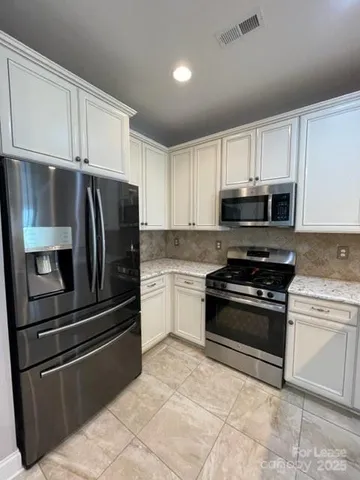 a kitchen with granite countertop white cabinets and stainless steel appliances