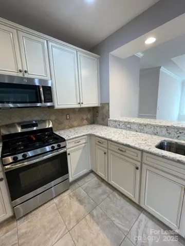 a kitchen with granite countertop a stove sink and cabinets