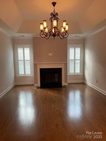 a view of a livingroom with a fireplace wooden floor and chandelier