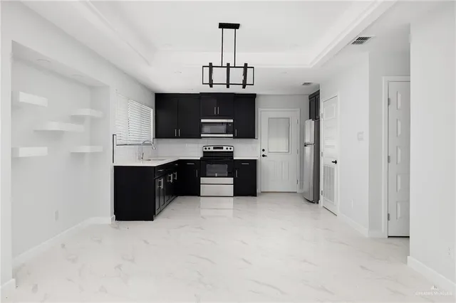 a kitchen with stainless steel appliances granite countertop a stove top oven a sink dishwasher and a refrigerator with wooden cabinets