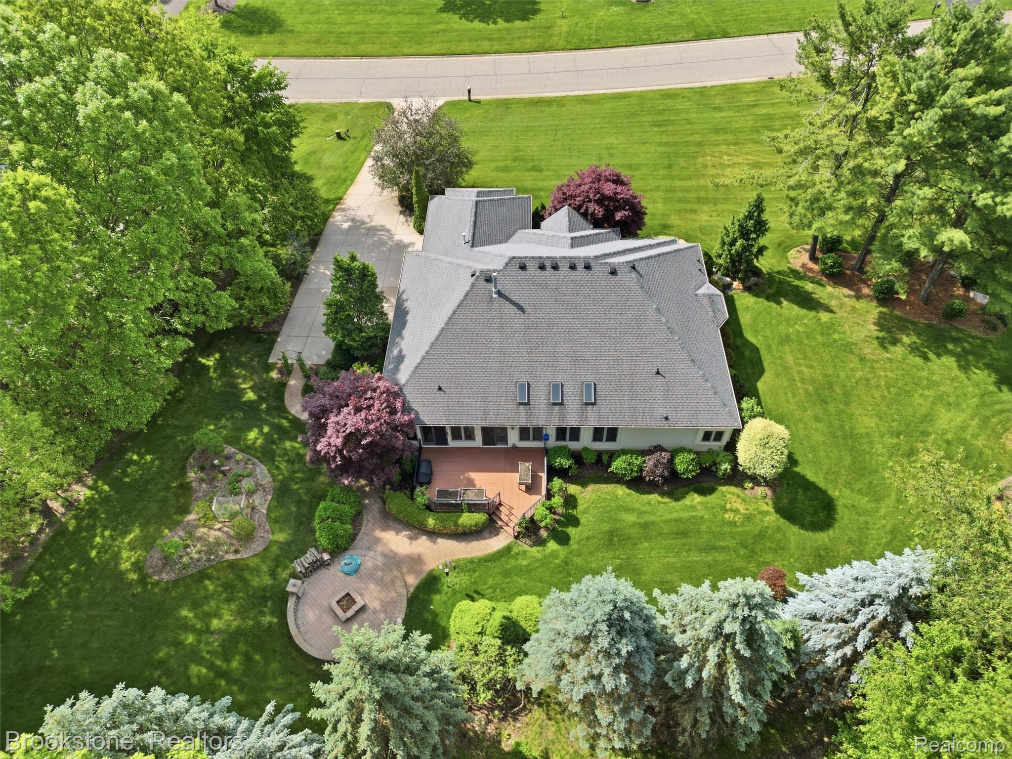 9523 Quail Ridge Run Brighton, MI 48114 - Photo 10 of 50 Expansive property showcasing a concrete driveway, a multi-level rear patio, and a circular fire pit area