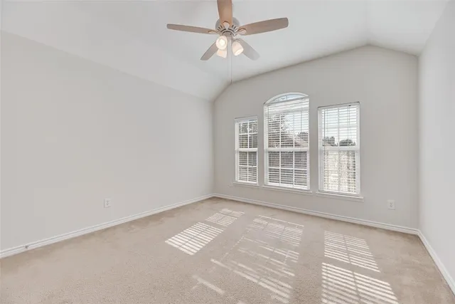 an empty room with windows and ceiling fan