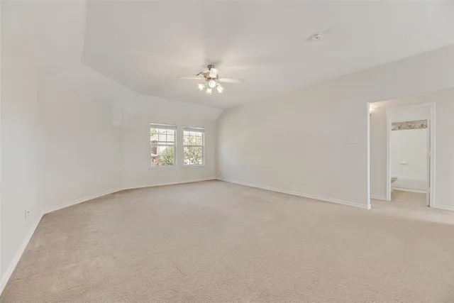 an empty room with a chandelier fan and windows