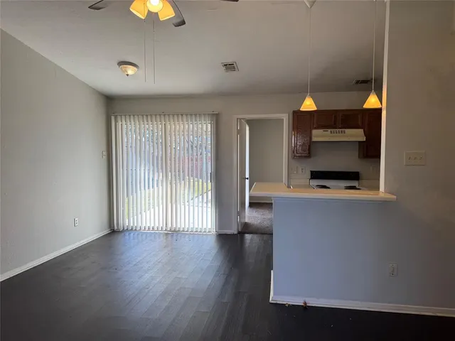 an empty room with wooden floor fireplace and windows