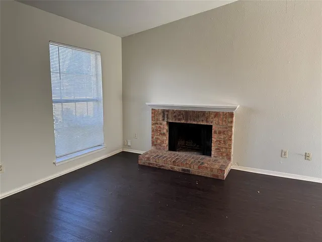 an empty room with fireplace and wooden floor