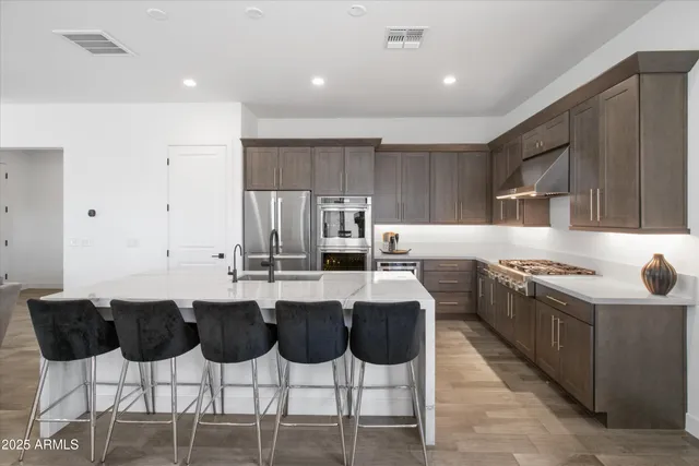 a kitchen with stainless steel appliances granite countertop a stove top oven a sink a dining table and chairs