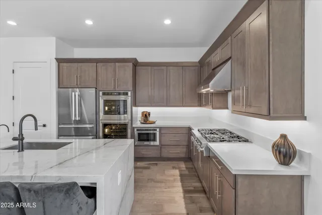 a kitchen with kitchen island stainless steel appliances a sink a stove and cabinets