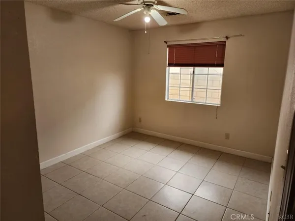 an empty room with a ceiling fan and window
