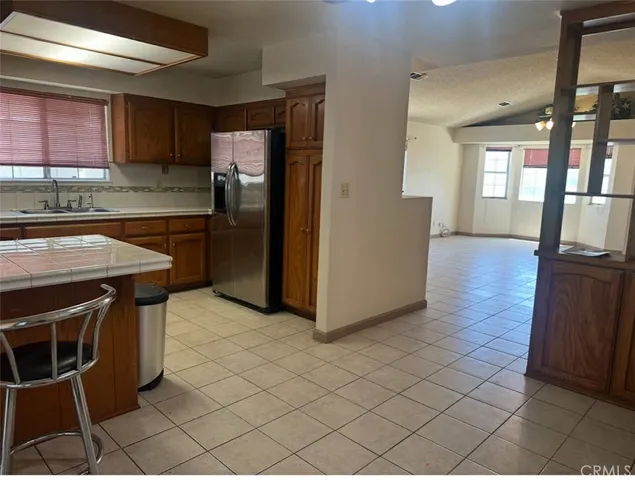 a kitchen with granite countertop a refrigerator a stove top oven and sink