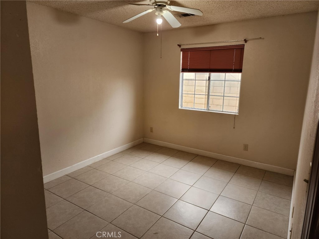 725 18th Place Delano, CA 93215 - Photo 20 of 36 an empty room with a ceiling fan and window