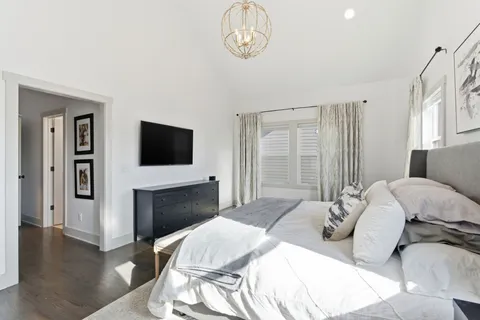 a spacious bedroom with a bed a dresser and large window