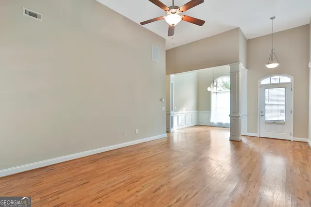 a view of an empty room with wooden floor and a window