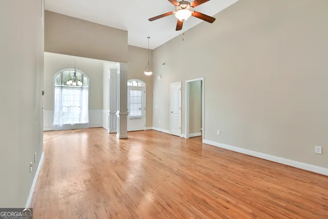 an empty room with wooden floor and a ceiling fan
