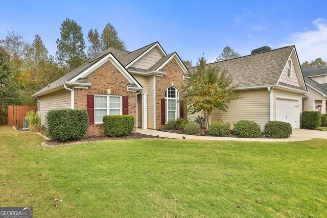 a view of a house next to a big yard and large trees
