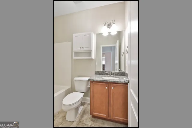 a bathroom with a granite countertop toilet a sink and a mirror