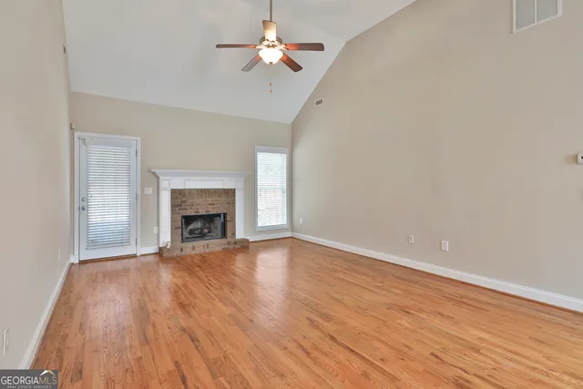 a view of empty room with wooden floor and fireplace