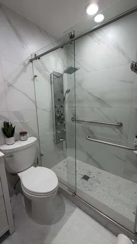 a white toilet next to a shower
