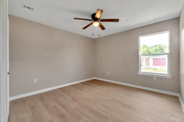 an empty room with a window and a fan