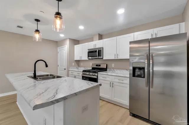 a kitchen with stainless steel appliances granite countertop a refrigerator a sink a stove a microwave and island