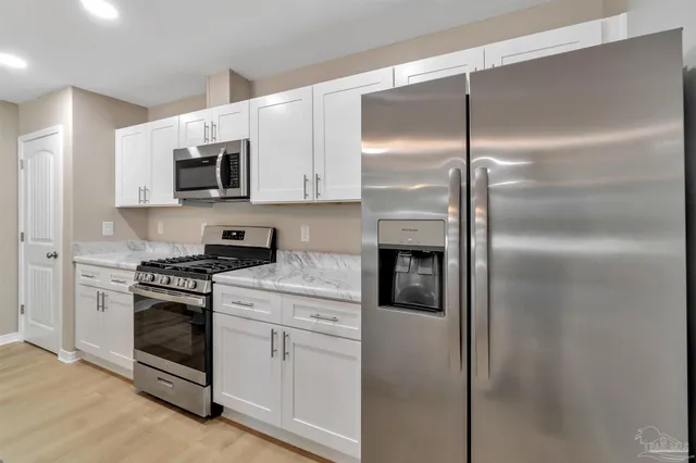 a kitchen with white cabinets and stainless steel appliances
