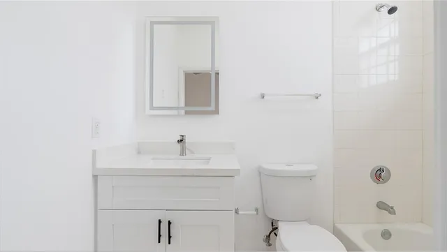 a bathroom with a toilet a sink a mirror and vanity