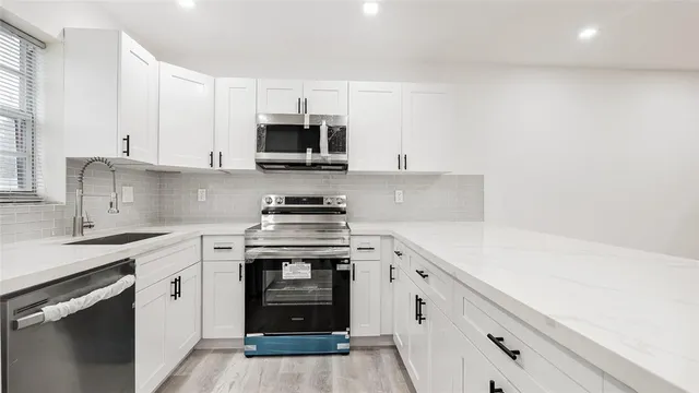 a kitchen with stainless steel appliances white cabinets and a sink