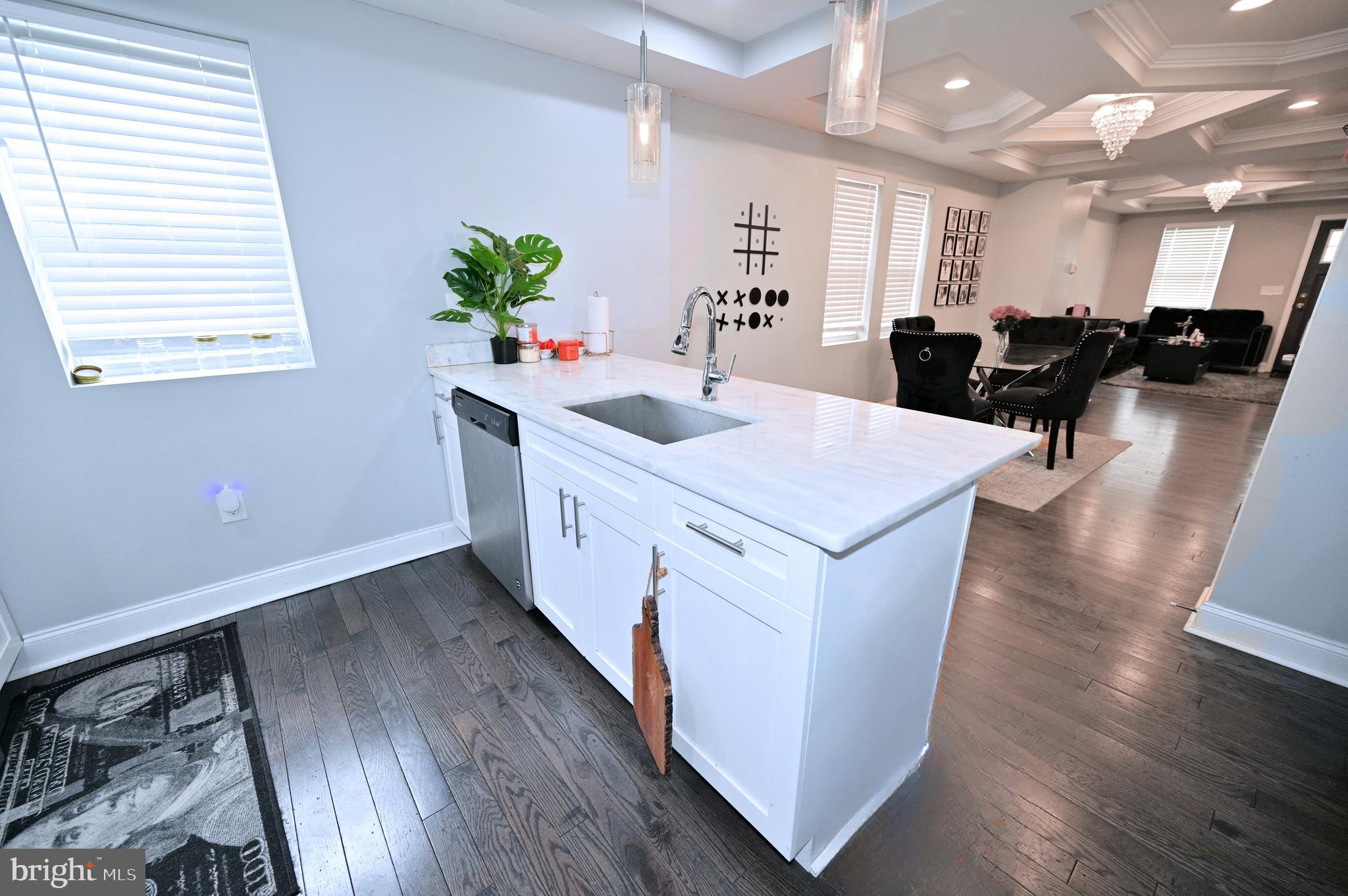 3700 Flowerton Road Baltimore, MD 21229 - Photo 4 of 30 a kitchen with stainless steel appliances granite countertop a sink dishwasher a stove a dining table and chairs with wooden floor