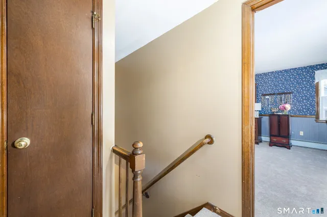 a bed sitting in a room next to a lamp with a bookshelf