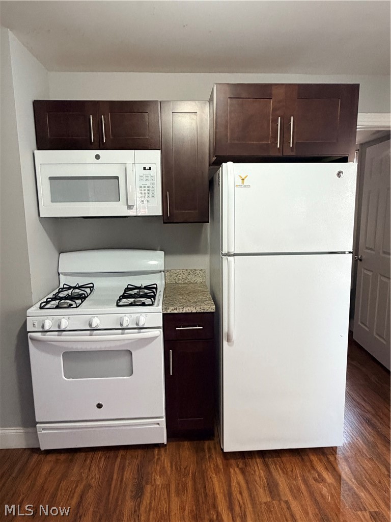 2017 Random Road Cleveland, OH 44106 - Photo 10 of 20 Kitchen featuring wood-finish flooring, white appliances, dark wood cabinetry, and a countertop